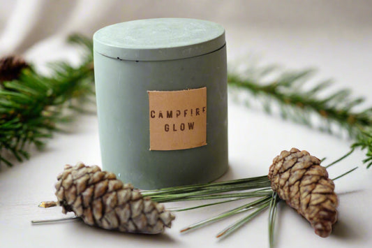 a small candle surrounded by pine cones